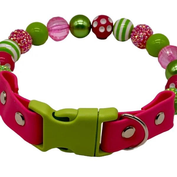 The Lime and Pink Beaded Dog Collar showcases decorative beads with polka dots, stripes, and textured designs in pink, green, and red. It features a vibrant pink and green clasp and D-ring for a colorful pet accessory.