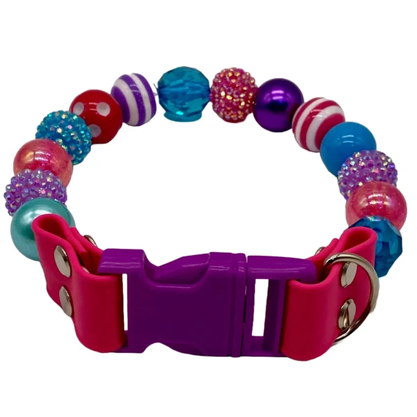 A colorful beaded dog collar featuring vibrant round beads in blue, pink, purple, and red, some with glitter or stripes. It has a purple buckle with a pink latch and includes two metal rings.