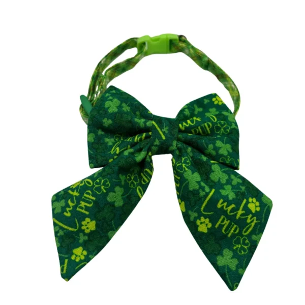 The Lucky Pup Adjustable Collar, ideal for small dogs or cats, is green with a buckle strap. It features a large bow tie adorned with shamrocks, paw prints, and the words Lucky Pup in yellow, combining style and easy fitting.